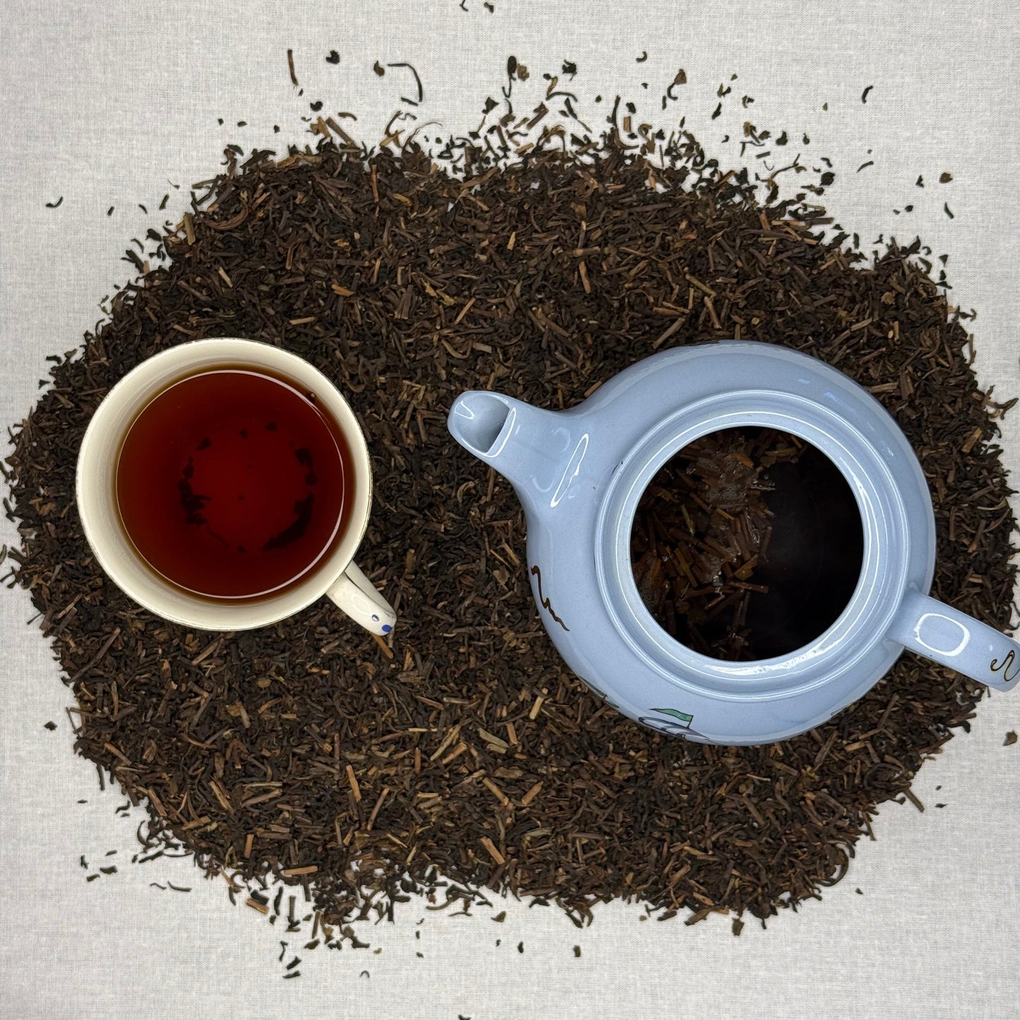 Decaffeinated Tea leaves with a teapot and cup on a textured surface