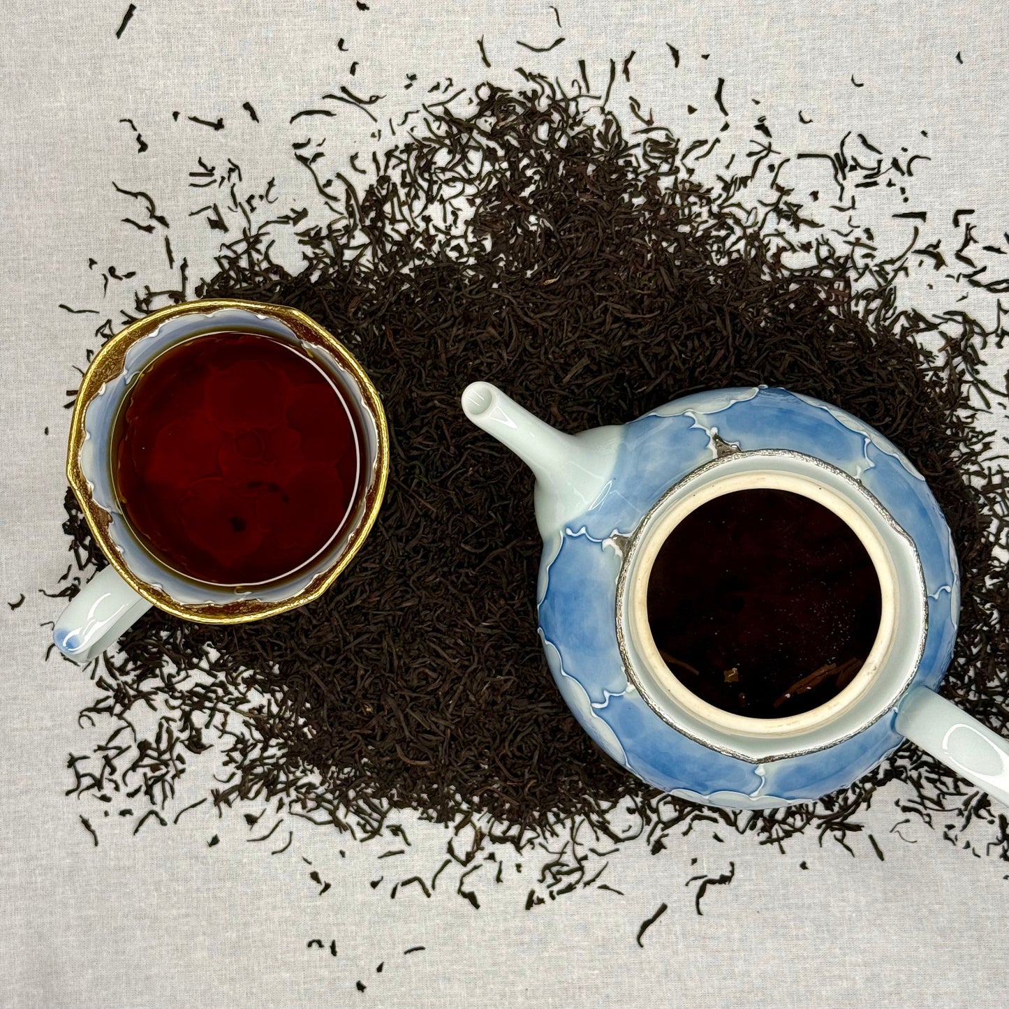 Tea cup and teapot with scattered tea Earl Grey Tea on a textured surface