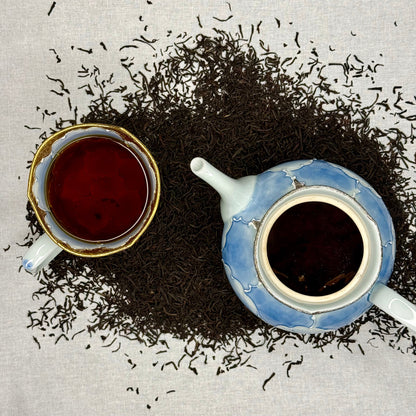 Tea cup and teapot with scattered tea Earl Grey Tea on a textured surface