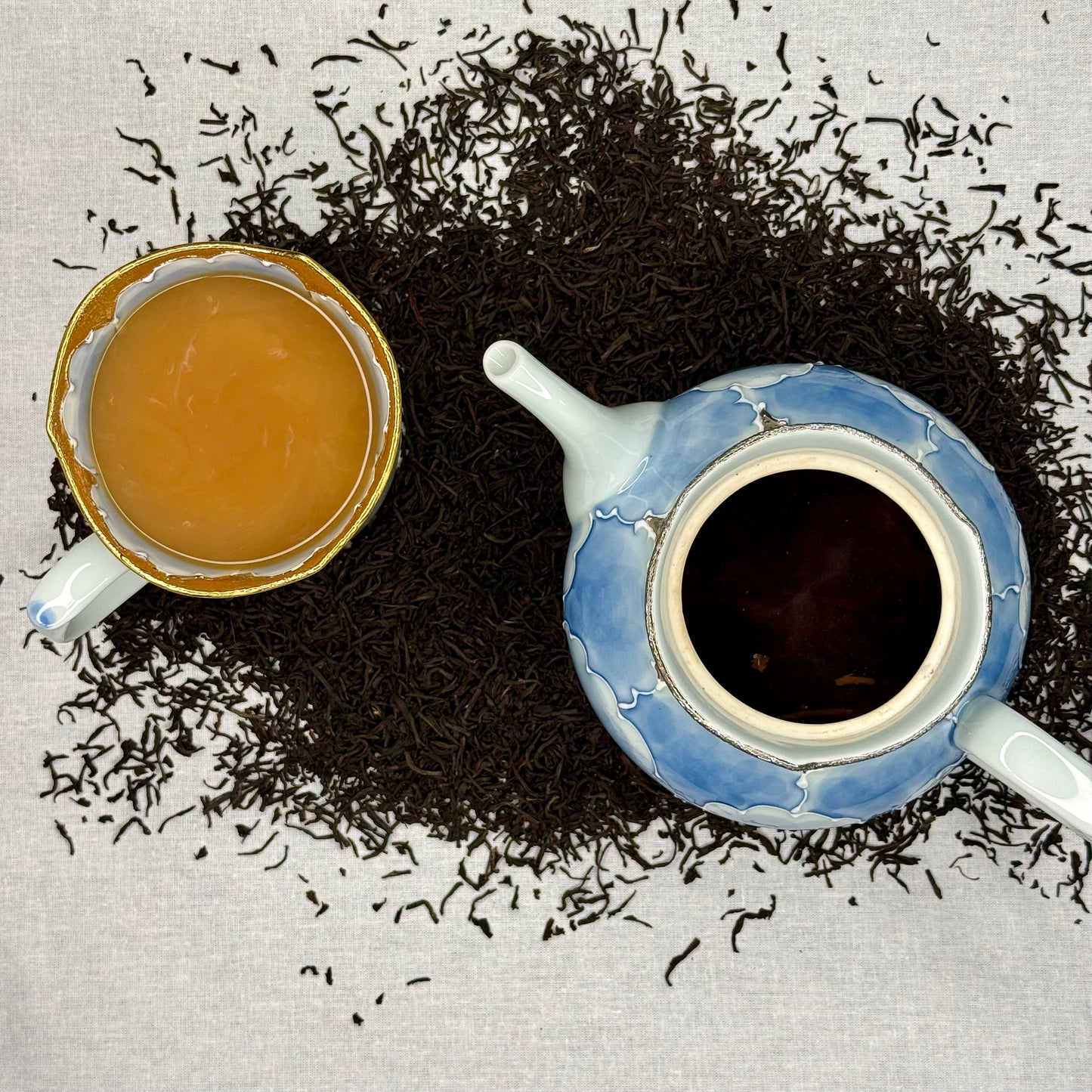 Earl Grey tea leaves and a teacup with tea and Milk on a textured surface